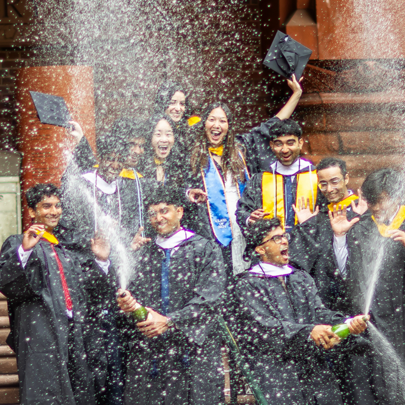 Students in academic regalia spraying champagne in celebration